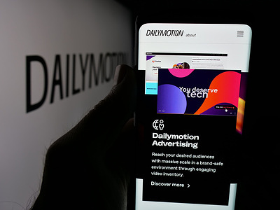 In this photo illustration, a cellphone with the webpage of French video sharing company Dailymotion S.A. is seen on screen in front of logo.