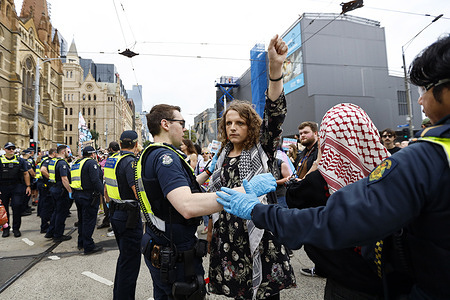 A protester raises a fist as police block the rally near Flinders Street Station. The National Day of Action calls for the reversal of Queensland’s decision to pause prescribing puberty blockers and HRT to new public health patients under 18. Advocates argue that gender-affirming care is medically necessary and life-saving for trans youth. The move echoes policies seen in the U.S where restrictions on trans healthcare have led to broader rollbacks on bodily autonomy. Protesters warn that if left unchallenged, this decision could set a precedent for nationwide restrictions. A rally in front of the Victoria State Library aims to pressure the government to overturn the policy and uphold the rights of trans youth.
