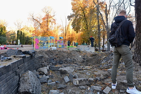 People seen near the crater from the explosion of a Russian rocket on a children's playground in the center of the capital. After several months of relative calm, multiple explosions rocked Kyiv early on a Monday morning. The head of the Ukrainian military said that Russian forces launched at least 75 missiles at Ukraine, with fatal strikes targeting the capital Kyiv, and cities in the south and west.