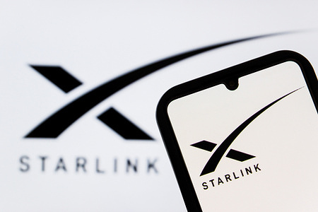 In this photo illustration, a Starlink logo is displayed on a smartphone screen, and in the background.