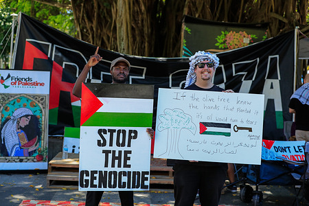 Members of Free Palestine FNQ and BLAKtivation hold placards during a protest in solidarity with Palestine at the Cairns Esplanade.