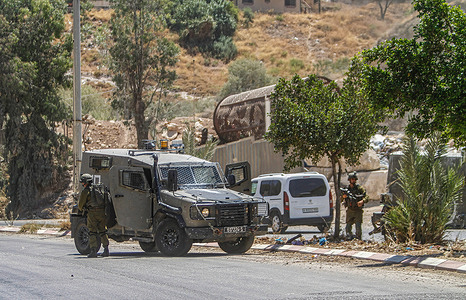 Israeli soldiers stand guard next to their military patrol vehicles during the siege of the area near the site of the shooting attack on a car of Jewish settlers, near the settlement of Hamra in the northern West Bank. A speeding car opened fire on a car belonging to settlers near Al-Hamra settlement, wounding them. The Israeli army continues to surround the area to arrest the perpetrator.
