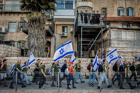 An Ultra-orthodox Jewish family on a balcony looks at protesters marching toward the Ultra-orthodox neighborhood of Mea Shearim. Dozens of protesters from the Brothers in Arms movement staged a demonstration inside Jerusalem's ultra-Orthodox Mea Shearim neighborhood, calling for the community to be drafted to the Israel Defense Forces (IDF), Sunday had been the deadline for the government to come up with legislation to resolve the issue but Netanyahu filed a last-minute application to the Supreme Court for a 30-day moratorium.