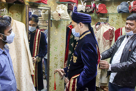 A salesman seen helping a groom to wear his suit and turban at a shop before his wedding ceremony during the coronavirus pandemic in Dhaka.
Many weddings were postponed due to the coronavirus pandemic. Since the pandemic situation in Bangladesh is getting better day by day, the social and cultural program like wedding ceremonies are reorganized in new normal way.