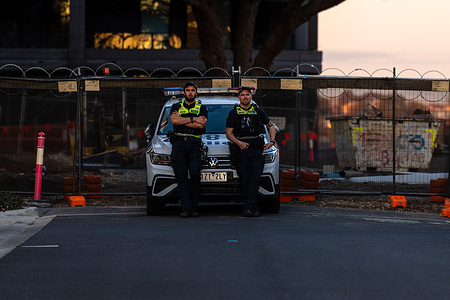 Security officers rest on the bonnet of a police car positioned at a closed-off road outside the ALP Conference venue. Protesters gathered outside the Australian Labor Party (ALP) Conference at Moonee Valley Racecourse voicing opposition to federal and state government policies. The demonstration calls for immediate recognition of Palestine, an end to military ties with Israel, protection of public housing and defence of union rights. Organised by grassroot groups including Free Palestine Coalition Naarm and public housing advocates, the protest also condemned anti-protest laws and Indigenous deaths in custody. Activists urged the ALP to take a stronger stand on justice, equity and human rights. Protesters failed to see or disrupt the conference.