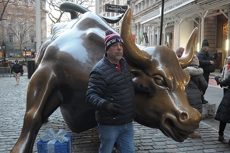 A person takes photos by the "Charging Bull" statue in the Financial District in Manhattan, New York City.