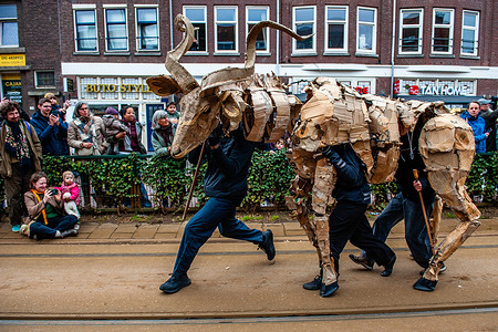 Men seen running with one of the creatures. THE HERDS, a public art and climate performance action featuring creatures made of ecological materials. They marched on the streets symbolizing their stampede from climate disaster. The procession started in Kinshasa (Democratic Republic of the Congo) and travels through various countries towards the North Pole symbolizing a serious theme the consequences of climate change.
They now continue their global tour as part of the ICAF (International Community Arts Festival).