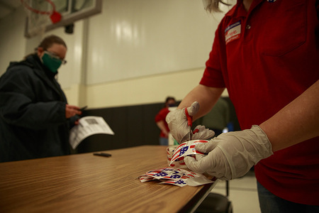 A poll worker cuts up “I voted” stickers during voting for the 2020 election at St. John the Apostle Catholic Church.
Polling stations across the United States open for voters to cast their vote for the 2020 presidential election