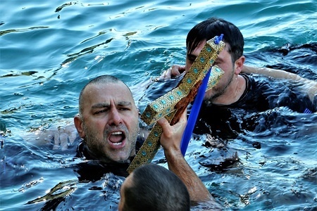 An orthodox believer seen holding a wooden crucifix during the annual Epiphany Day and the blessing of the waters in the Piraeus port.