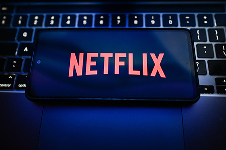 In this photo illustration, a Netflix logo is seen displayed on a smartphone on the top of a laptop.