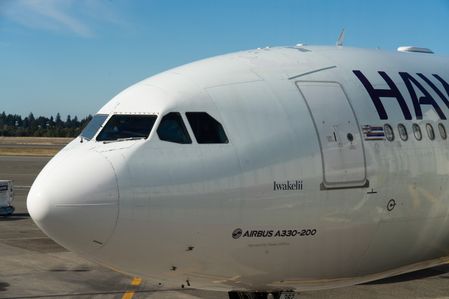 A Hawaiian Airlines Airbus A330-200 aircraft sits parked at a terminal gate at Seattle-Tacoma International Airport.