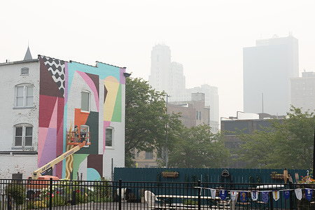 Connor Degnan, aka’ed as the artist ConTron, works on a mural on the Davis Building while Canadian wildfires pollute the air in downtown Toledo. Toledo experienced its worst air quality on record, as the Air Quality Index (AQI) reached upwards of 600.