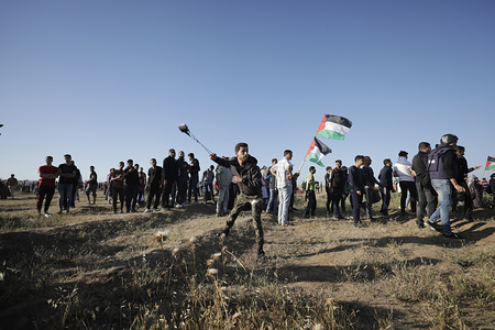 A Palestinian protester seen using a slingshot to hurl stones at Israeli troops during clashes on the Gaza-Israel border, east of Gaza City. 
At least 50 Palestinians were injured in clashes between demonstrators who joined the weekly anti-Israel protests and Israeli soldiers stationed on the border between eastern Gaza Strip and Israel, medics said.