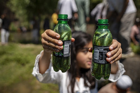 A girl holds bottle filled with fish at Panzath festival. Panzath Fish Festival, a traditional community event that combines fishing with the cleaning and restoration of freshwater springs. Participants wade through the shallow waters using baskets and hand nets to catch fish while simultaneously removing silt, weeds, and debris to maintain the natural flow of the springs.