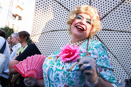 A female artist in a retro costume with an umbrella seen during the ceremonial procession of the street theatre festival on Elagin Island in St. Petersburg. The festival opened on the evening of July 26 with a theatrical procession from the Krestovsky Ostrov metro station to Maslyany Lug on Elagin Island. Artists in colorful costumes performed interactive acts for the audience, including dances, games, improvisations, and large round dances.