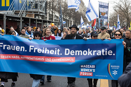 Activists Karoline Preisler and Rabbi Yehuda Teichtal along with other protesters carry a banner calling to stop antisemitism and oppose extremism during the rally. A pro-Israel rally against antisemitism and extremism took place in the city center, featuring activist Karoline Preisler and Rabbi Yehuda Teichtal. The demonstration started at the Brandenburg Gate and continued through the surrounding area.