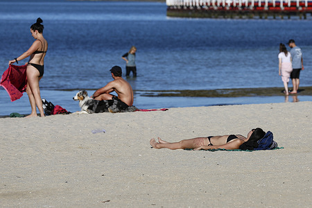 A woman lies on the sand sunbathing at Geelong Beach during hot weather. People gather at Geelong Beach as Victoria experiences extreme heat, with Melbourne reaching a maximum of 36 °C today. Hot conditions are forecast to continue, with Melbourne expected to reach around 33 °C tomorrow. The Bureau of Meteorology has issued a severe heatwave warning for Victoria, advising residents to stay hydrated, limit sun exposure, and follow heat-health guidance.