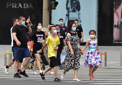 Tourists wearing facemasks as a precaution against the spread of covid-19 walk along Wangfujing Commercial Street in Beijing.