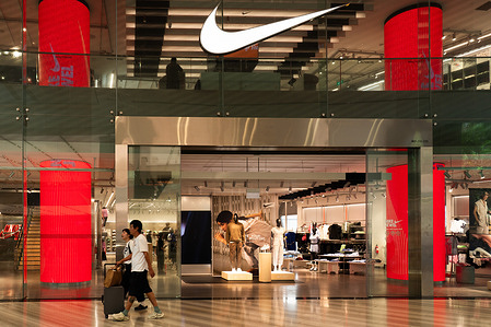 Pedestrians walk past an American multinational sportswear corporation Nike store.