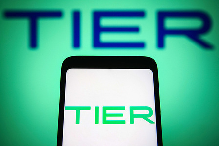 In this photo illustration, a TIER Mobility AG logo is seen on a smartphone and a pc screen.