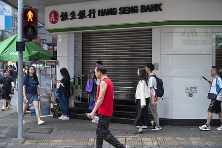 Pedestrians walk past the Hong Kong-based banking and financial services company, Hang Seng Bank, branch in Hong Kong.