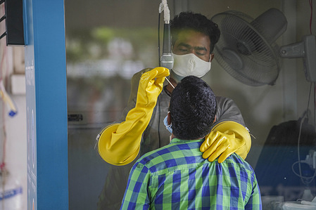 An employee wearing a facemask collects a swab sample from a resident to be tested for coronavirus.
Mugda Medical College and Hospital employees collect samples from residents to be tested for the coronavirus (COVID-19) disease.