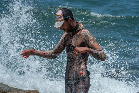A young Egyptian fisherman wearing a wetsuit arranges his net on the Mediterranean Sea front of Alexandria, second largest city in Egypt.