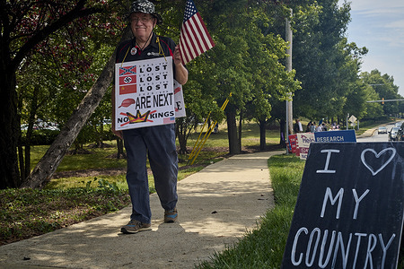 A protester holds an American flag and a placard expressing his opinion during a weekly demonstration. Protesters from the Indivisible, a progressive non-profit founded in 2016 by former congressional staffers, stage a demonstration along Generals Highway in hopes to push back against the Trump administration through non-violent resistance from small, local groups across the US.