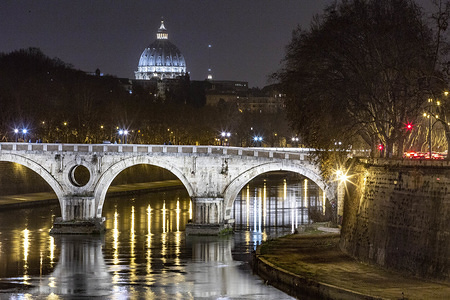 A view of a bridge accross the Tiber river in Rome at night.