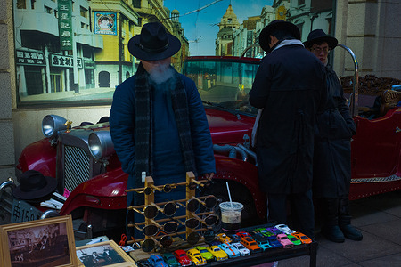 A young seller in 1930s Old Shanghai men’s fashion suits smokes at a stall on the Walking Street of Nanjing Road.
