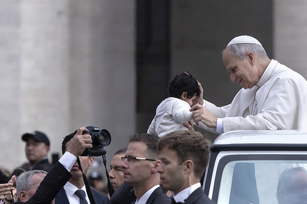 Pope Leo XIV greets a child as he arrives for his weekly general audience at St. Peter's square.