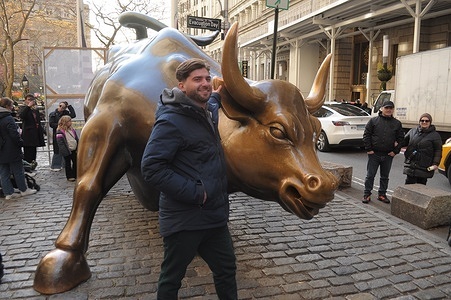 A person takes photos by the "Charging Bull" statue in the Financial District in Manhattan, New York City.