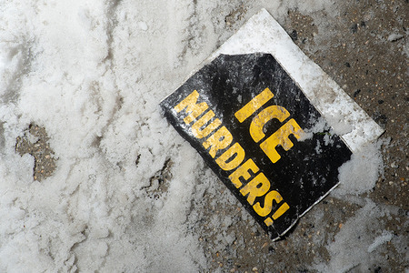 A placard is buried in the snow outside the Hilton Garden Inn during the rally. Similar to that in Minneapolis, Minnesota, activists stormed the hotel, which was reported to house Immigration and Customs Enforcement agents.