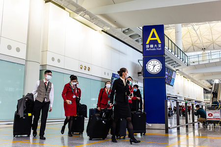 HONG KONG, CHINA - MARCH 19, 2020:
Flight attendants seen wearing face masks as protective measure against the Covid-19 coronavirus as they arrive at Hong Kong international airport.
 With the coronavirus outbreak worsening around the world, hundreds of passengers and students fly back to Hong Kong. Passengers were masked and several individuals covered themselves in protective dressing from head to toe.