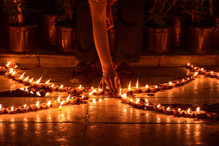 A Hindu woman lights an oil lamp on the occasion of Diwali, the Hindu festival of lights. Deepavali, also known as Diwali or the Festival of Lights, is a major Hindu festival celebrated worldwide between mid-October and mid-November. The festival symbolizes the victory of light over darkness and good over evil, marked by lighting lamps, exchanging sweets, and performing prayers for prosperity. Spanning five days, it includes rituals such as Dhanteras, Choti Diwali, Lakshmi Puja, Govardhan Puja, and Bhai Dooj, each celebrating themes of renewal, victory, and family bonds.