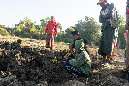 Villagers look into a bomb crater left by the airstrike. A 67-year-old woman from the village was killed, a man was injured, and at least five houses were damaged in the airstrike.