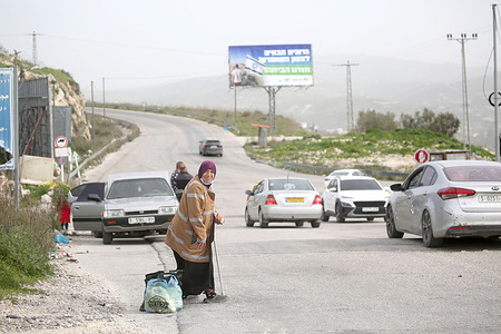 An elderly Palestinian woman waits near a sign erected by Jewish settlers on main roads and in areas under Palestinian Authority control between Nablus and Jenin. The sign, written in Hebrew, reads: "Welcome to Northern Samaria. We have returned to our homes in the West Bank." Local residents reported that Jewish settlers attacked Palestinian homes and farmers in villages south of Nablus, injuring four Palestinians. The Israeli government seeks to annex the West Bank.