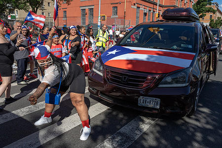 A woman twerks in front of a modified van during the 2024 Knickerbocker Avenue Puerto Rican Day Parade in Bushwick, Brooklyn. New York City celebrates its 6th Annual parade along Knickerbocker Avenue, to celebrate the culture, history and achievements of Puerto Rican Americans.