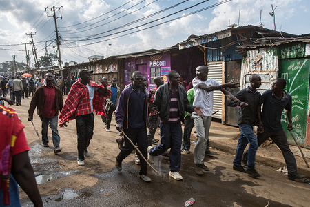 Youngsters and adults alike are escorting a man who didn't wanted to vote because of the queues on a street leading to primary school Olympics in the middle of Kibera Slum where the voting is taking place.