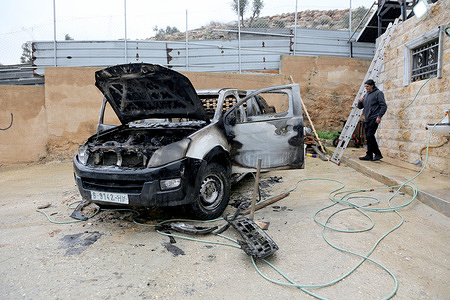 A Palestinian man seen walking past a burning car after Israeli settlers set fire on two Palestinian vehicles.