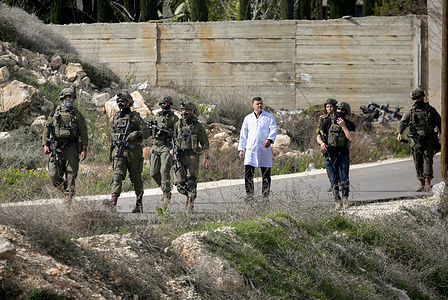 Israeli soldiers escorted a Palestinian doctor during the house raids following the intensive search for the perpetrator of the attack that targeted an Israeli vehicle near Mount Ebal in the West Bank city of Nablus. The Israeli military reported that its vehicle came under fire near Nablus after losing its way, and that Israeli forces raided Palestinian homes, arrested residents in the area, established military checkpoints, and imposed a security cordon around Mount Ebal.