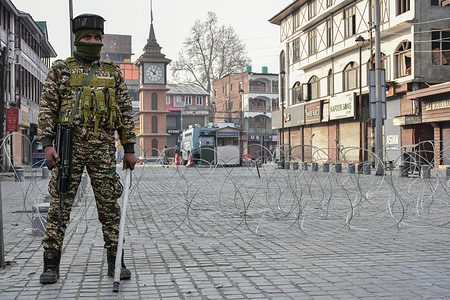 A paramilitary trooper stands guard near the concertina wire barricade during the restrictions imposed after protests erupted following the killing of Iran's Supreme Leader Ayatollah Ali Khamenei in Srinagar.