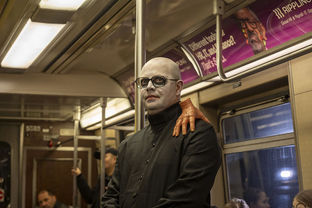 A reveler dress as Uncle Fester from the Addams Family rides the subway at Union Square/14 Street Subway Station.