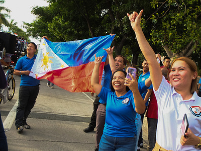 Filipino supporters waving their Philippine flag while the Philippine Athletes float arrives Filipinos chant in jubilation for the Philippine Olympians at the grand homecoming parade held in Manila led by Olympic double gold medalist Carlos Yulo & Bronze medalist Nesthy Petecio & Aira Villegas .