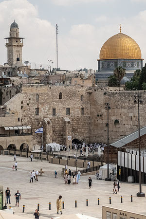 Jewish worshippers and tourists in the area of the Western Wall. The Western Wall, also known as the Wailing Wall or Al Buraq Wall, is a pilgrimage site for Jewish believers in the Old City of Jerusalem. It is part of the Temple Mount's retaining wall and is divided by a partition, with men on the left and women on the right. Jewish visitors pray, read from the Torah, and leave handwritten notes, known as kvitlachim, in the wall’s cracks. This centuries-old tradition is based on the belief that a divine presence resides in the wall. The area is monitored by Israeli soldiers.