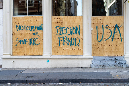View of a boarded up store with graffiti that reads “No Lockdown #2, Election Fraud, USA” amid Coronavirus crisis.