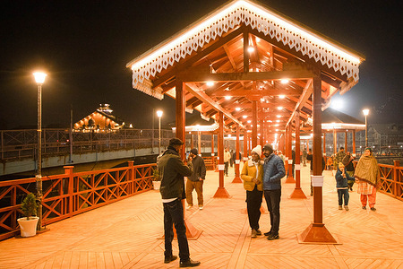 People take photos at the newly revamped Amira Kadal pedestrian bridge during the evening in Srinagar. The historic Amira Kadal was originally built in the eighteenth century during Afghan rule and has opened to the public after nearly two years of restoration work as part of efforts to modernize urban infrastructure while preserving historic assets. The bridge will serve as a pedestrian only crossing built at a cost of about $870,000, with its original foundations retained. Officials said the project is intended to enhance public movement and promote heritage aesthetics along the Jhelum riverfront while safeguarding the bridge’s historical character.