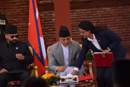 Newly elected speaker of the House of Representatives, Dol Prasad Aryal (DP) signs the documents after taking the oath of office while Prime Minister Balendra Shah (L) looks on during a swearing-in ceremony at Shital Niwas, the presidential office.