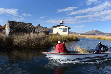 Uro family on board a motor boat sailing among the totora reed in Titicaca lake.
The Uru or Uros are indigenous people of Peru and Bolivia, who live on an approximate hundred floating islands, made of Totora reed, in Titicaca Lake near Puno. There are about 2.000 of them. The larger islands house 10 families while the small ones can be of only 30 metres wide hold 2 or 3 families.
