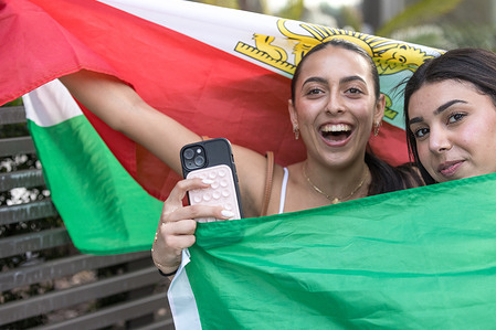 Two women pose while holding an Iranian flag during a rally in Los Angeles. The event was held in Westwood where members of the Iranian diaspora gathered to celebrate the reported death of Ayatollah Ali Khamenei and voice support for political change in Iran.